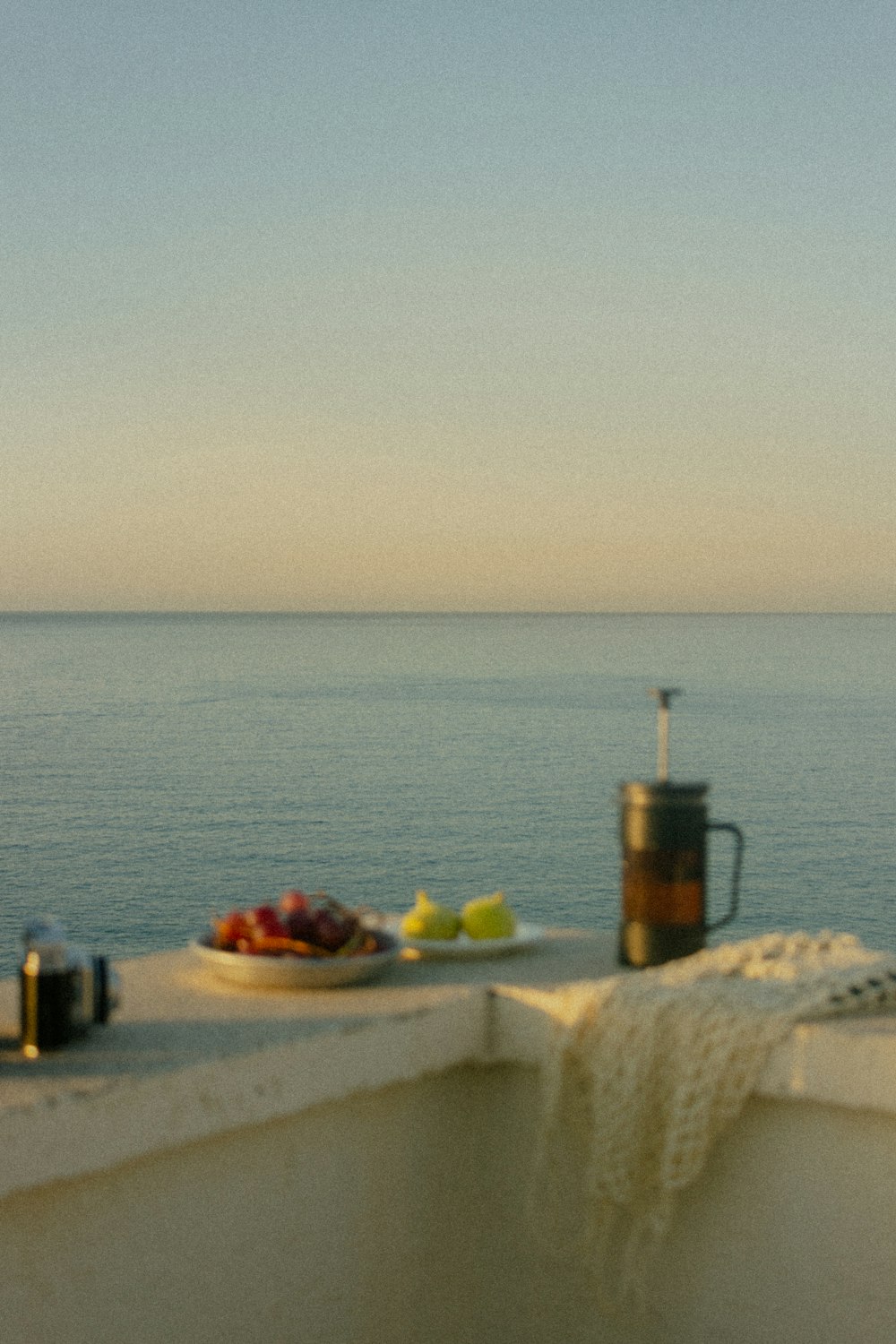 a bowl of fruit sitting on top of a table next to the ocean