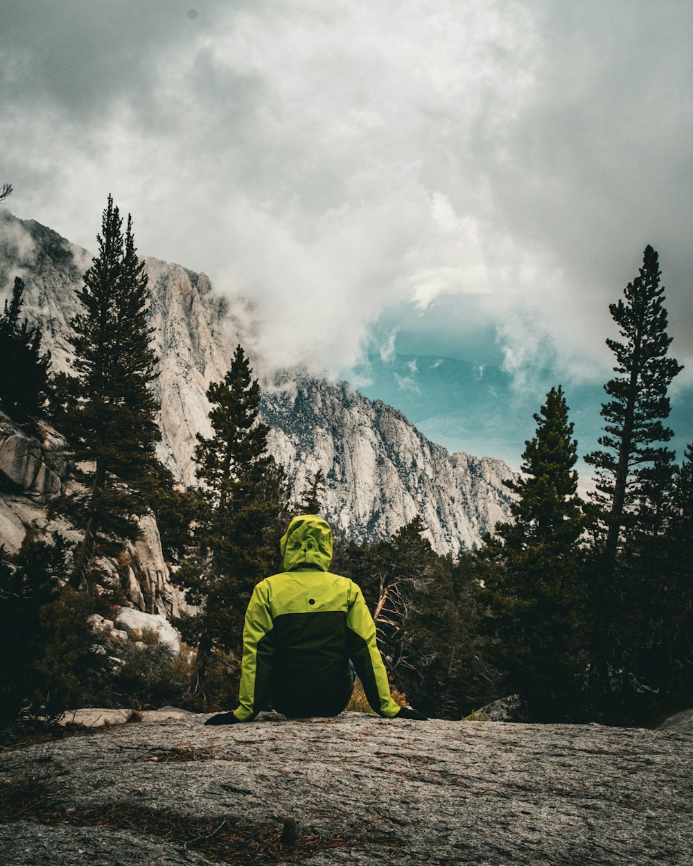 a person sitting on a rock in the mountains