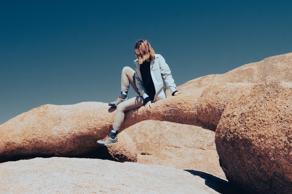 a woman sitting on top of a large rock