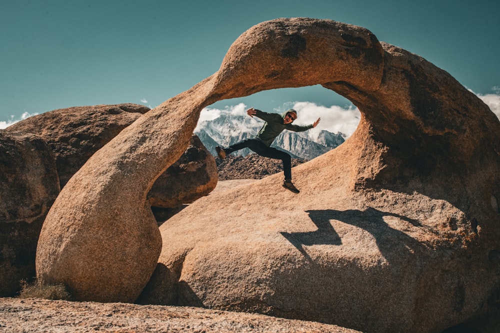um homem em pé no topo de uma grande formação rochosa
