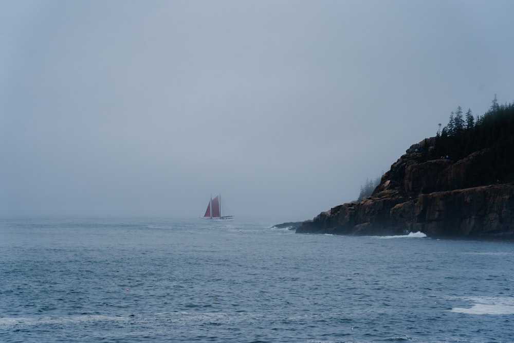 a sailboat in the ocean on a foggy day