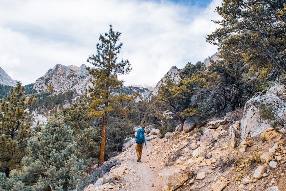 a man hiking up a trail in the mountains