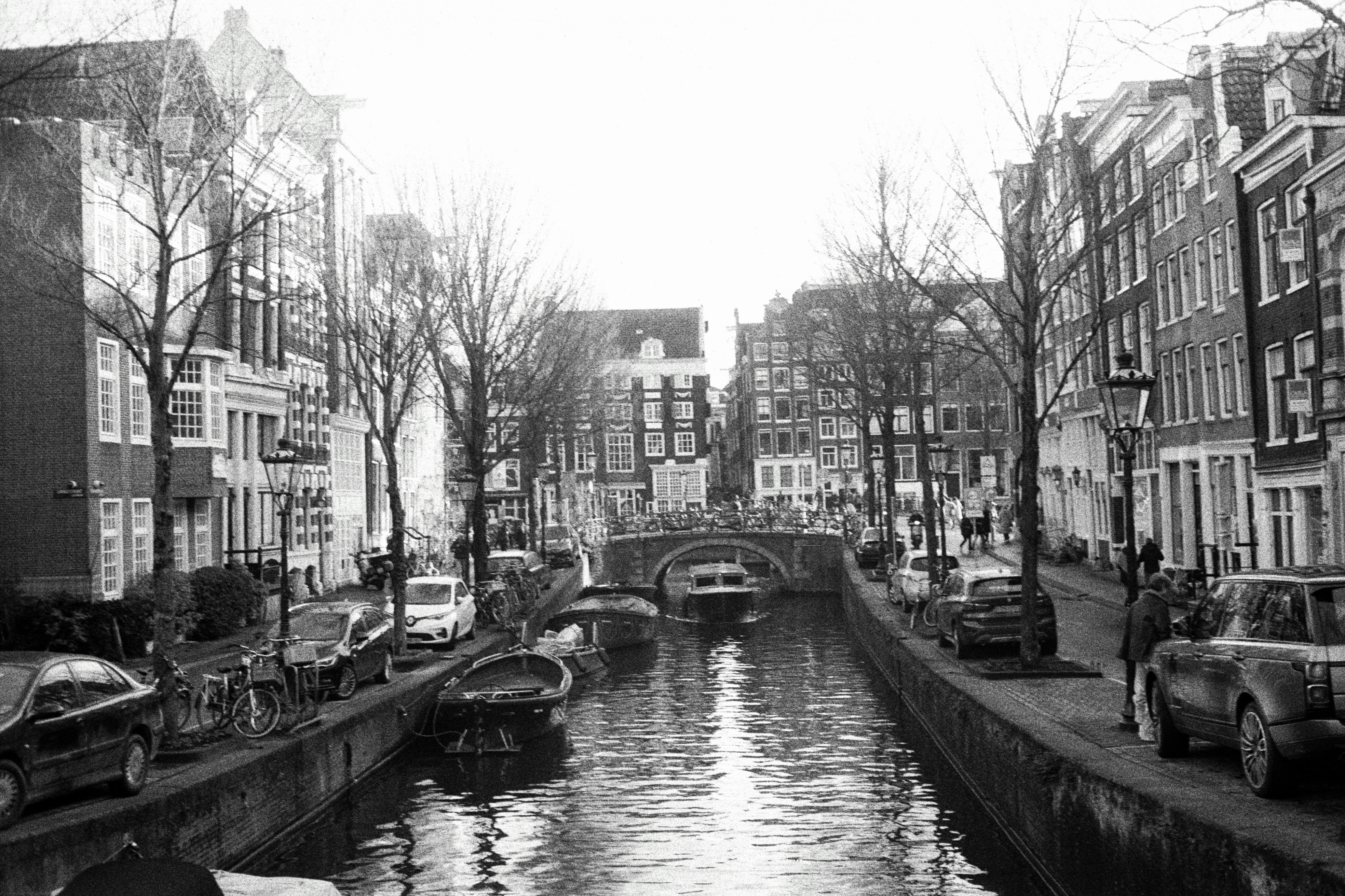 a black and white photo of a canal in a city