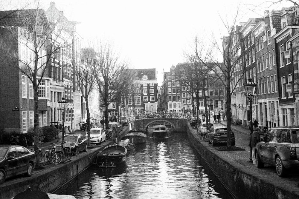 a black and white photo of a canal in a city