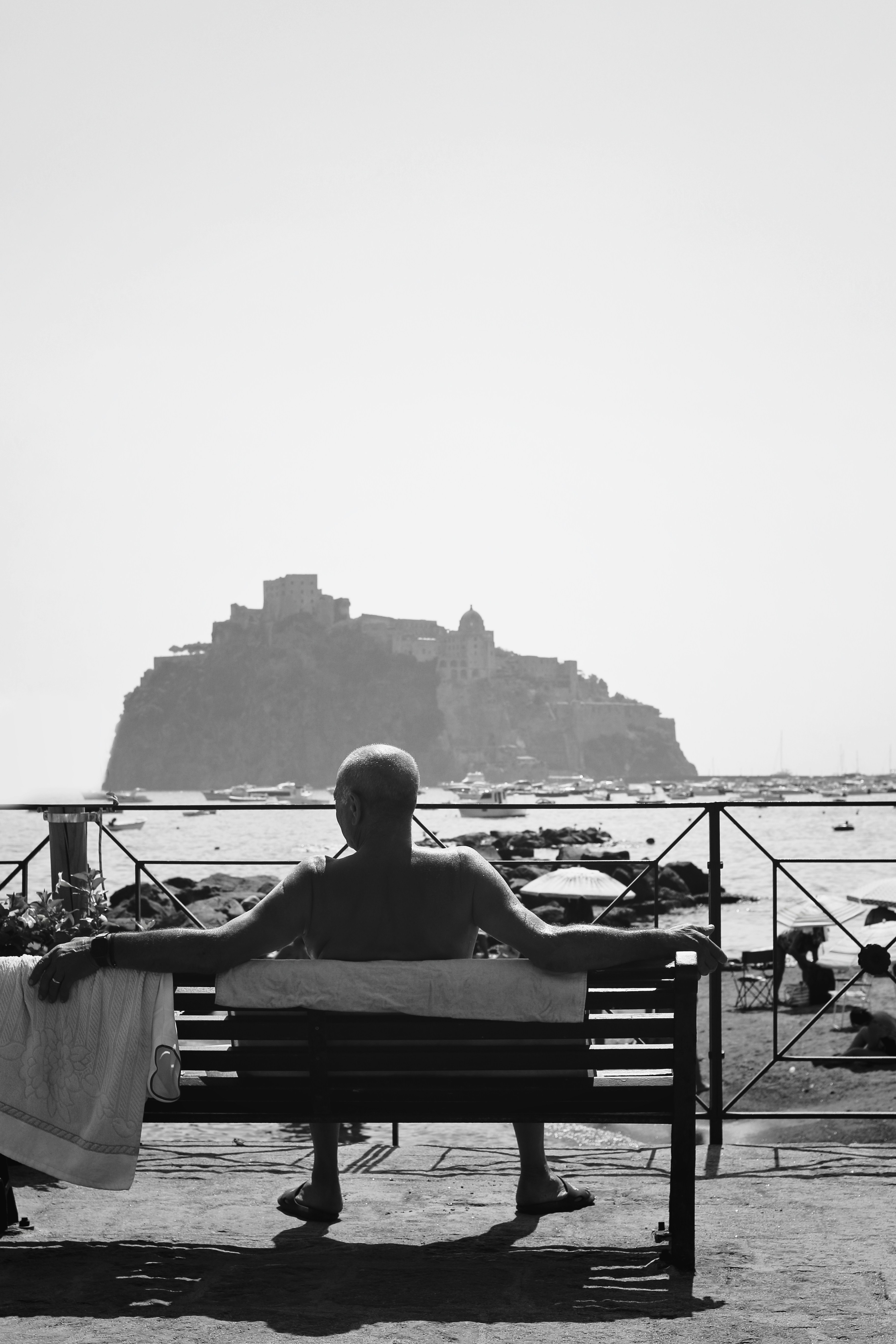 Un uomo seduto in cima a una panchina vicino all'oceano