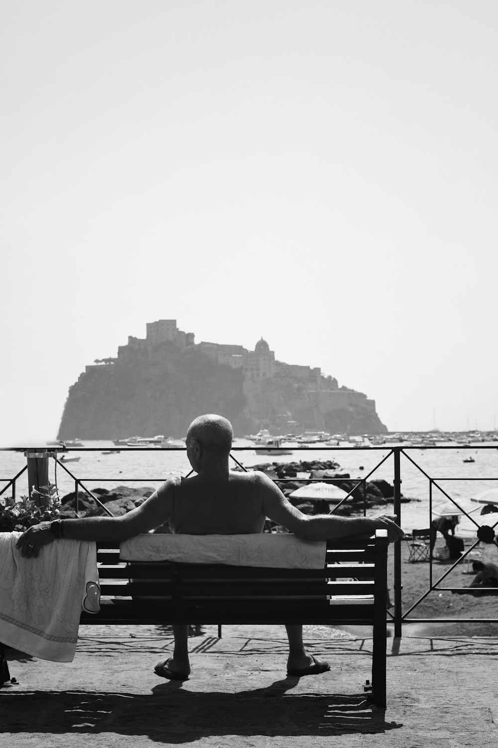 a man sitting on top of a bench next to the ocean