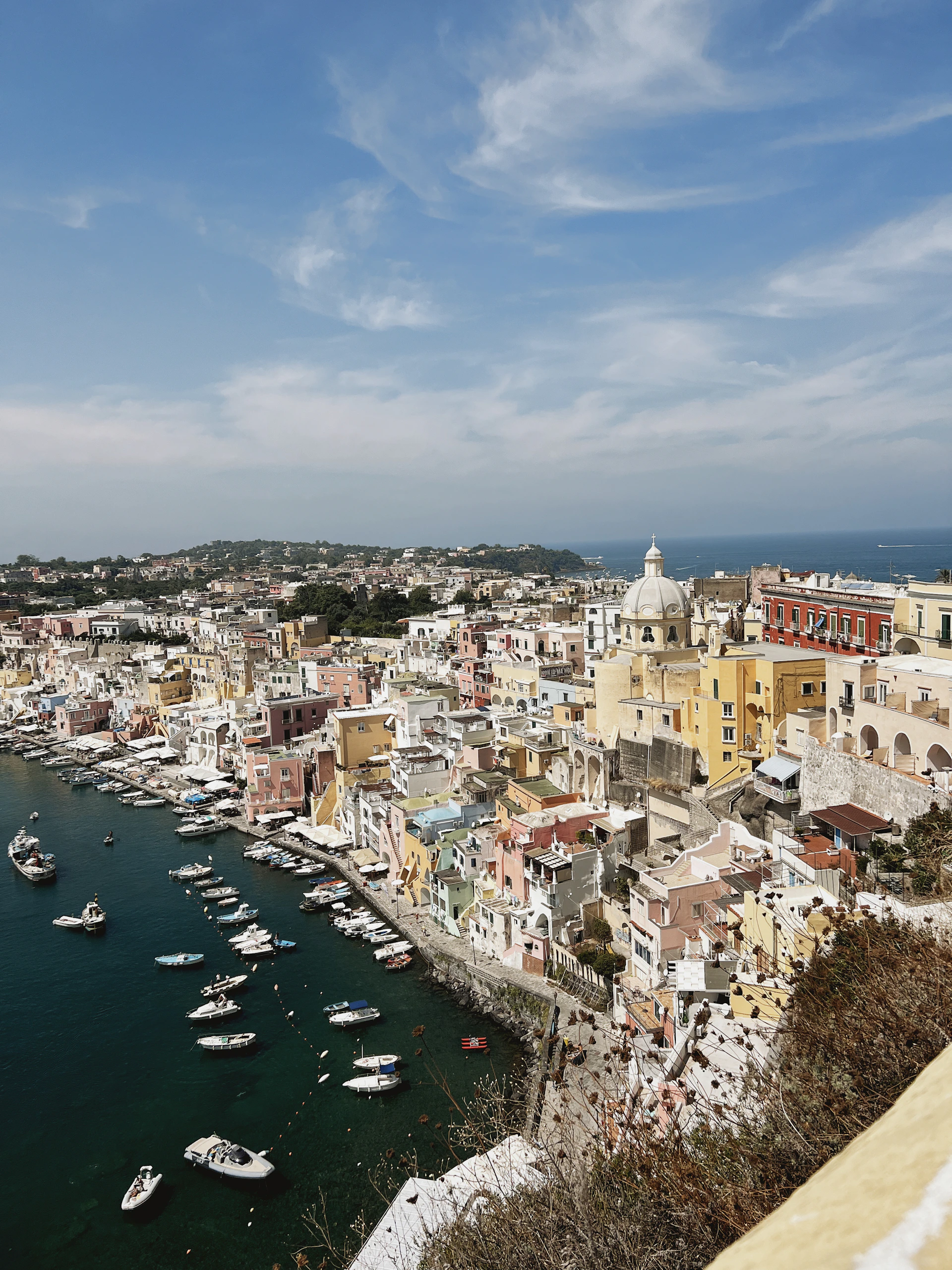A serene aerial view of the Amalfi Coast at sunset, with pastel-colored villas perched on cliffs above the sparkling Mediterranean Sea.