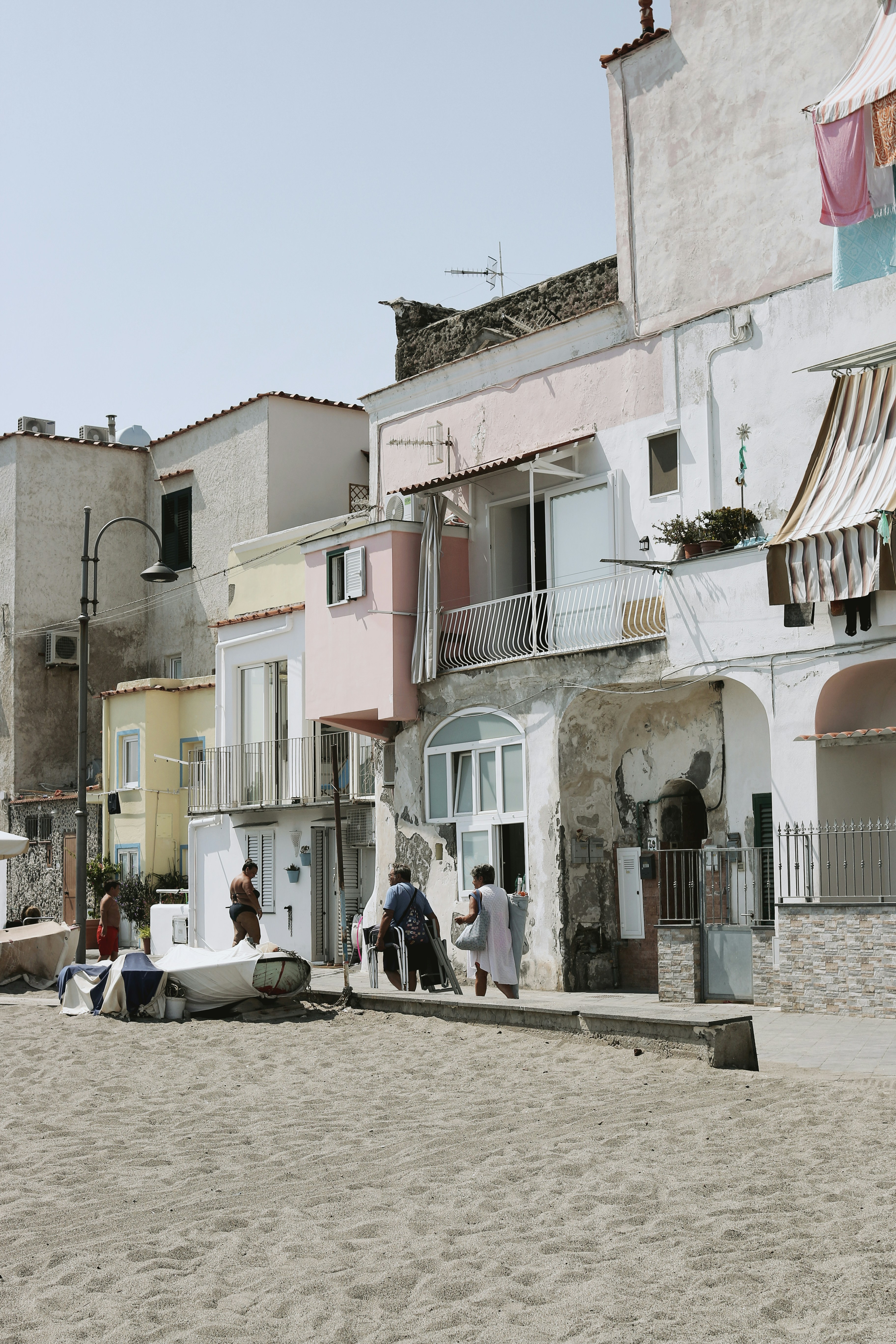 un groupe de personnes debout sur une plage à côté d’un bâtiment