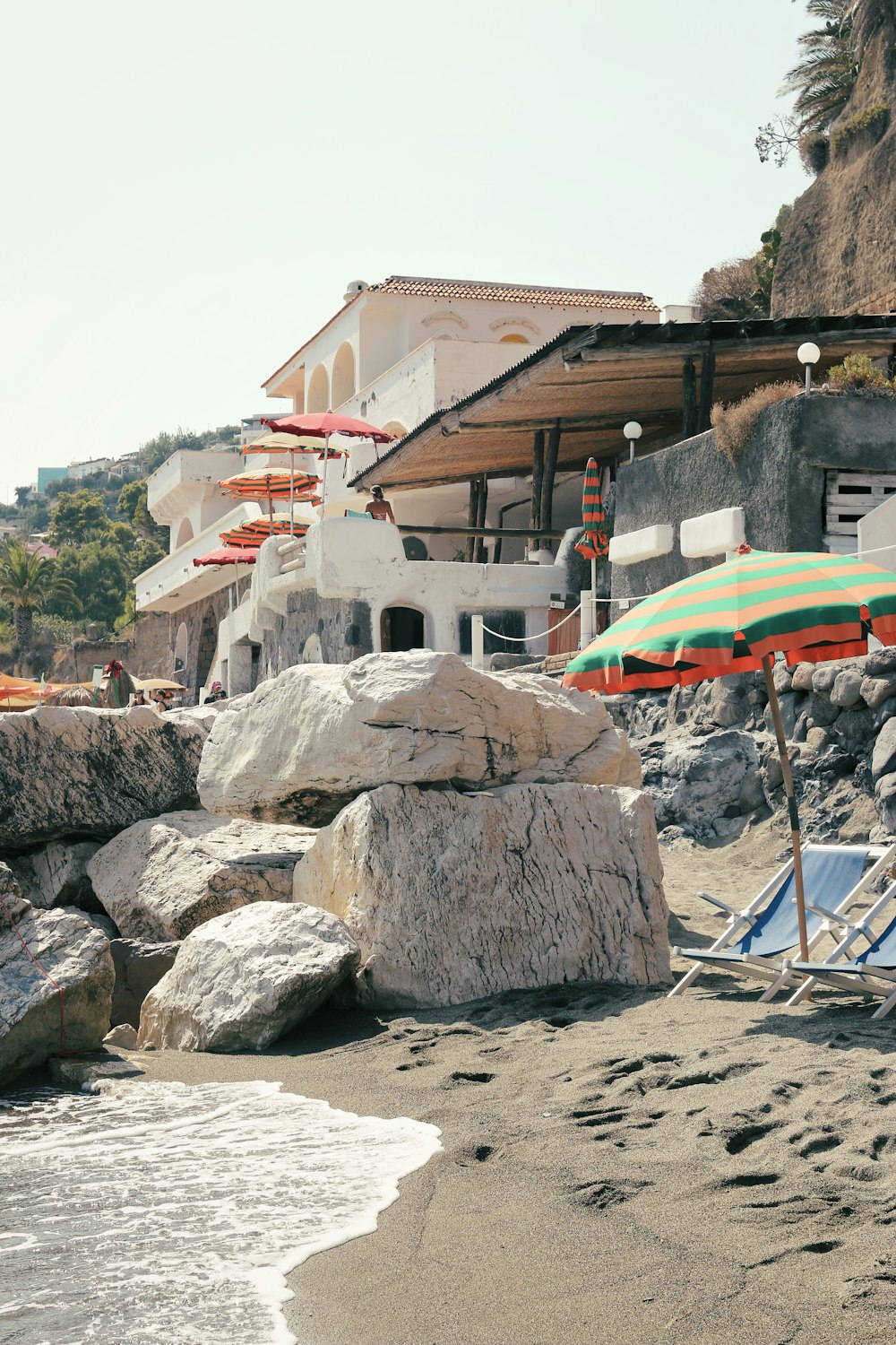 a beach with chairs and umbrellas next to the water