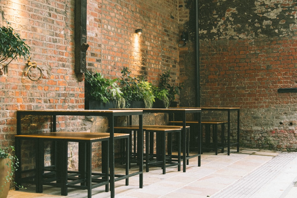 a row of wooden tables sitting next to a brick wall