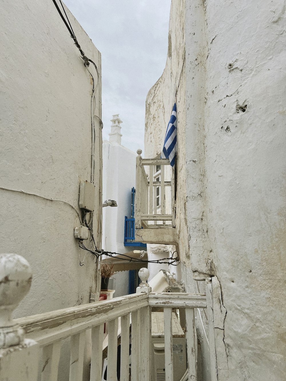 a narrow alleyway with white buildings and blue shutters