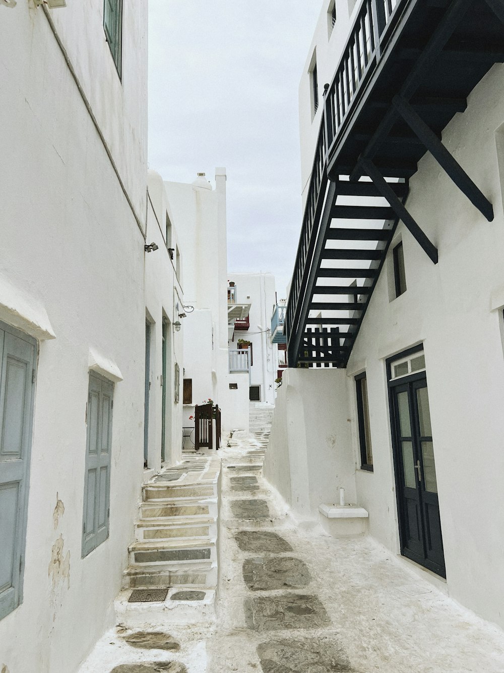 a narrow street with white buildings and stairs