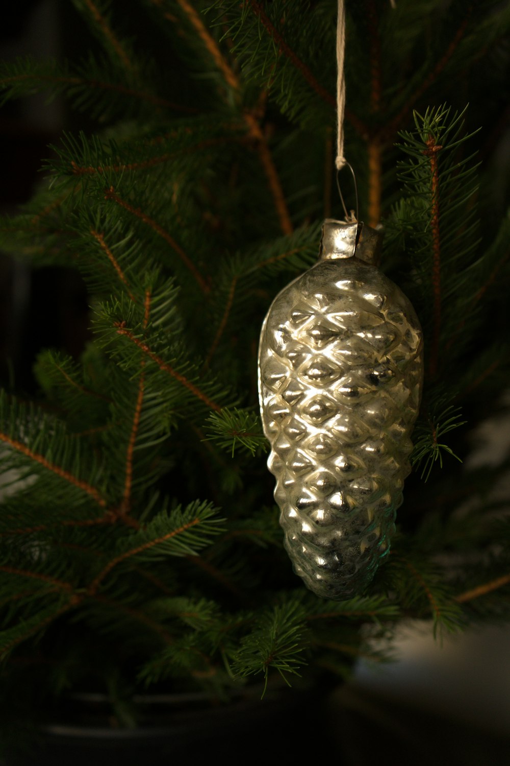 a silver ornament hanging from a christmas tree