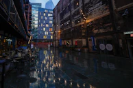 Golden city lights reflecting on wet cobblestone streets in an old European alley.