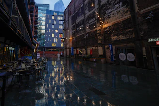 Golden city lights reflecting on wet cobblestone streets in an old European alley.