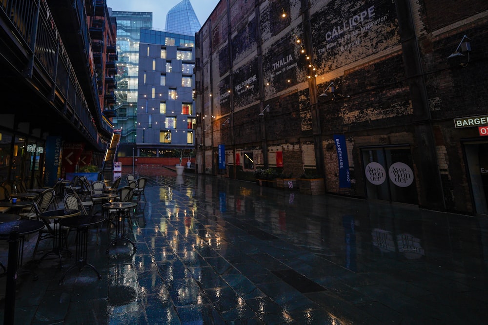 a city street with tables and chairs on a rainy day