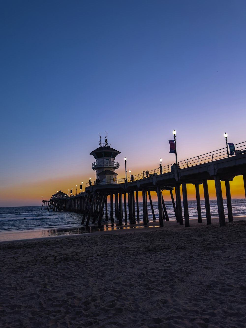 a pier at the beach with a light house in the background