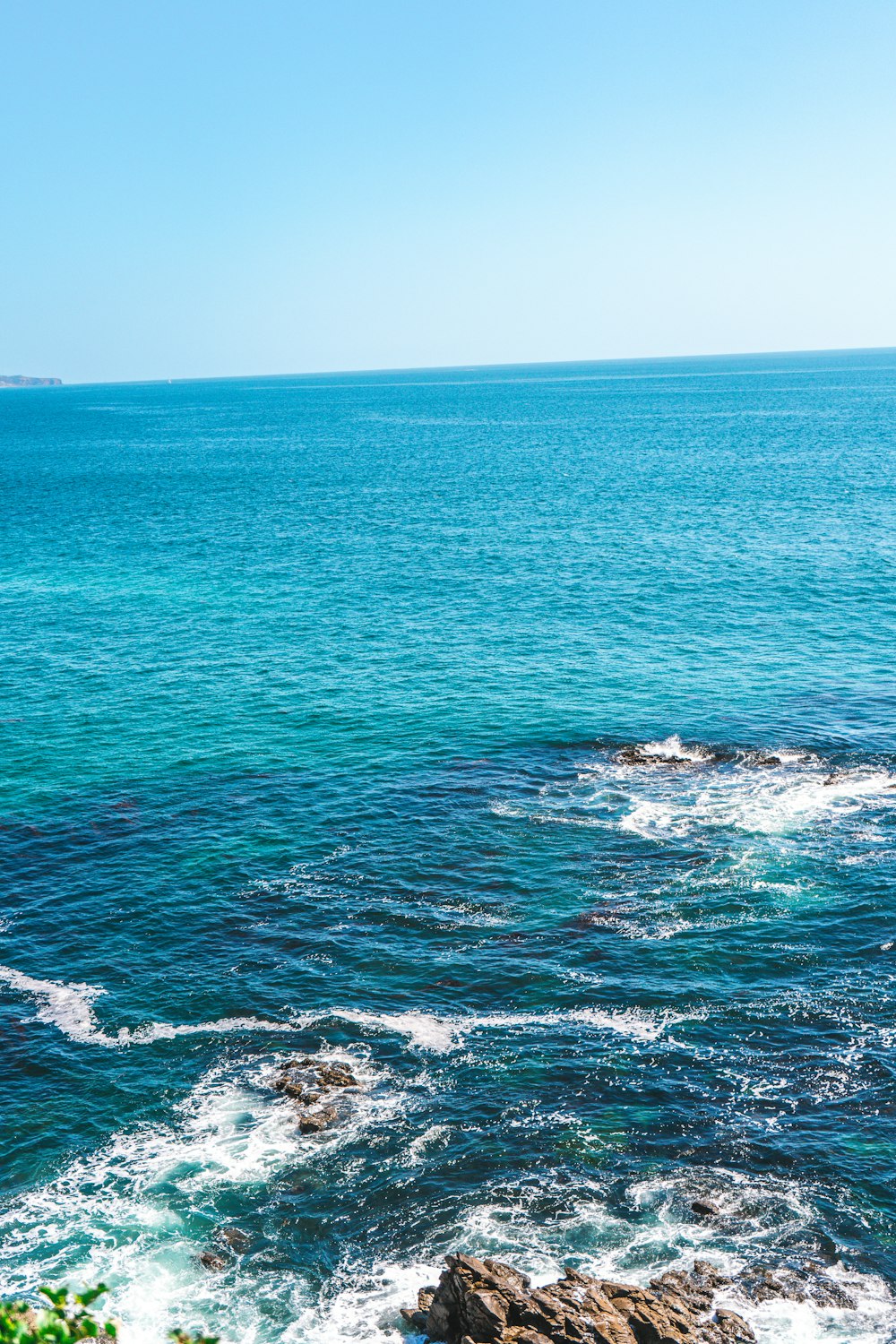 a large body of water sitting next to a lush green hillside