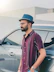 a man standing next to a car wearing a hat