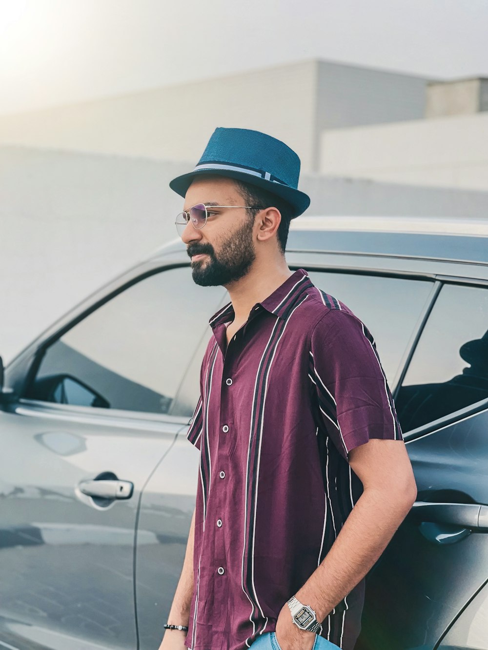 a man standing next to a car wearing a hat