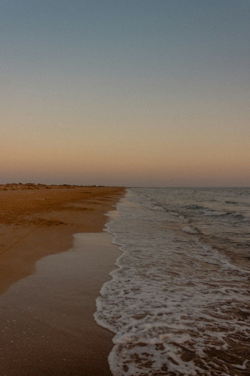 Una playa de arena con olas que llegan a la orilla