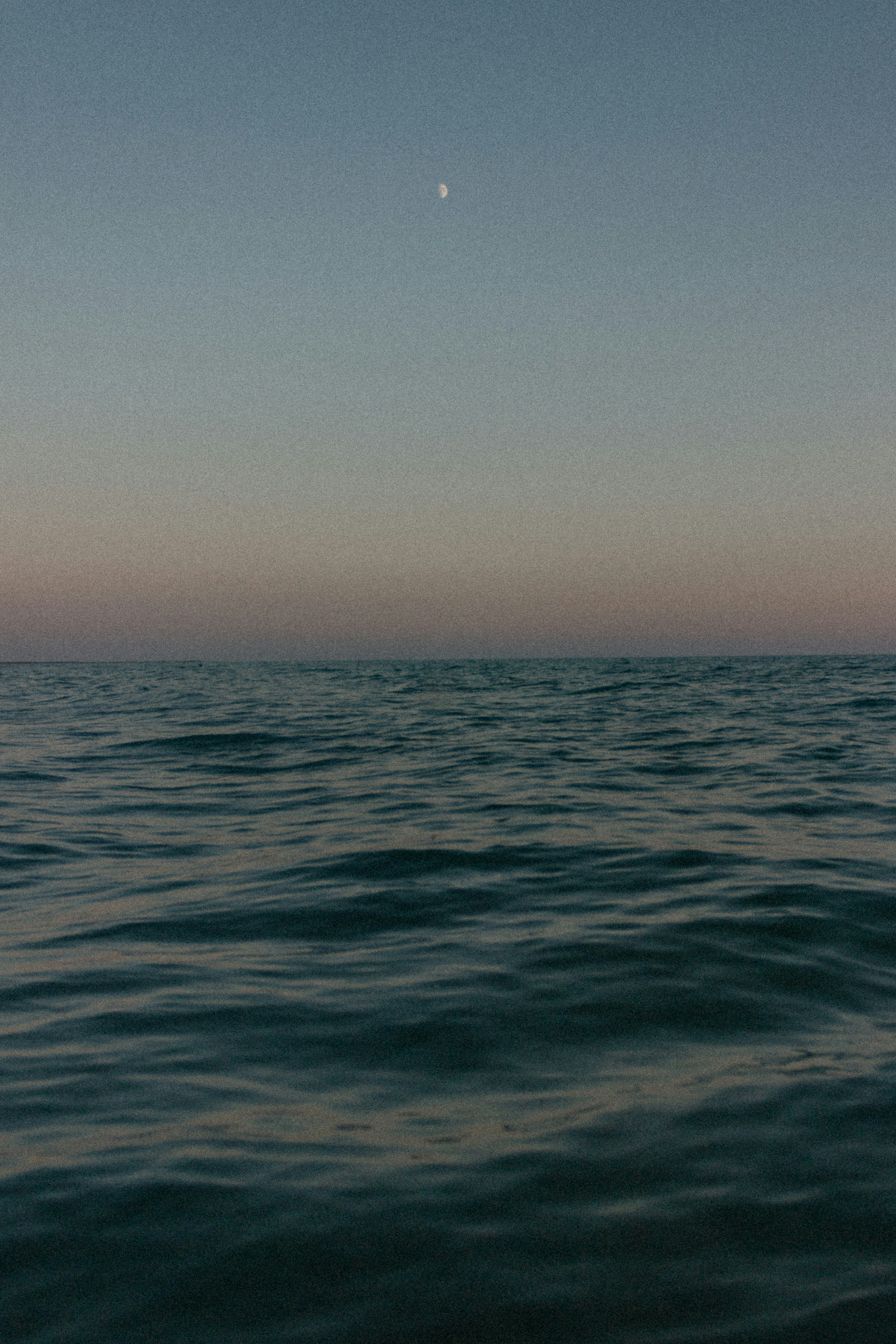 a body of water with a moon in the sky