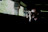 A shadowed figure observing from a distance with binoculars at dusk.