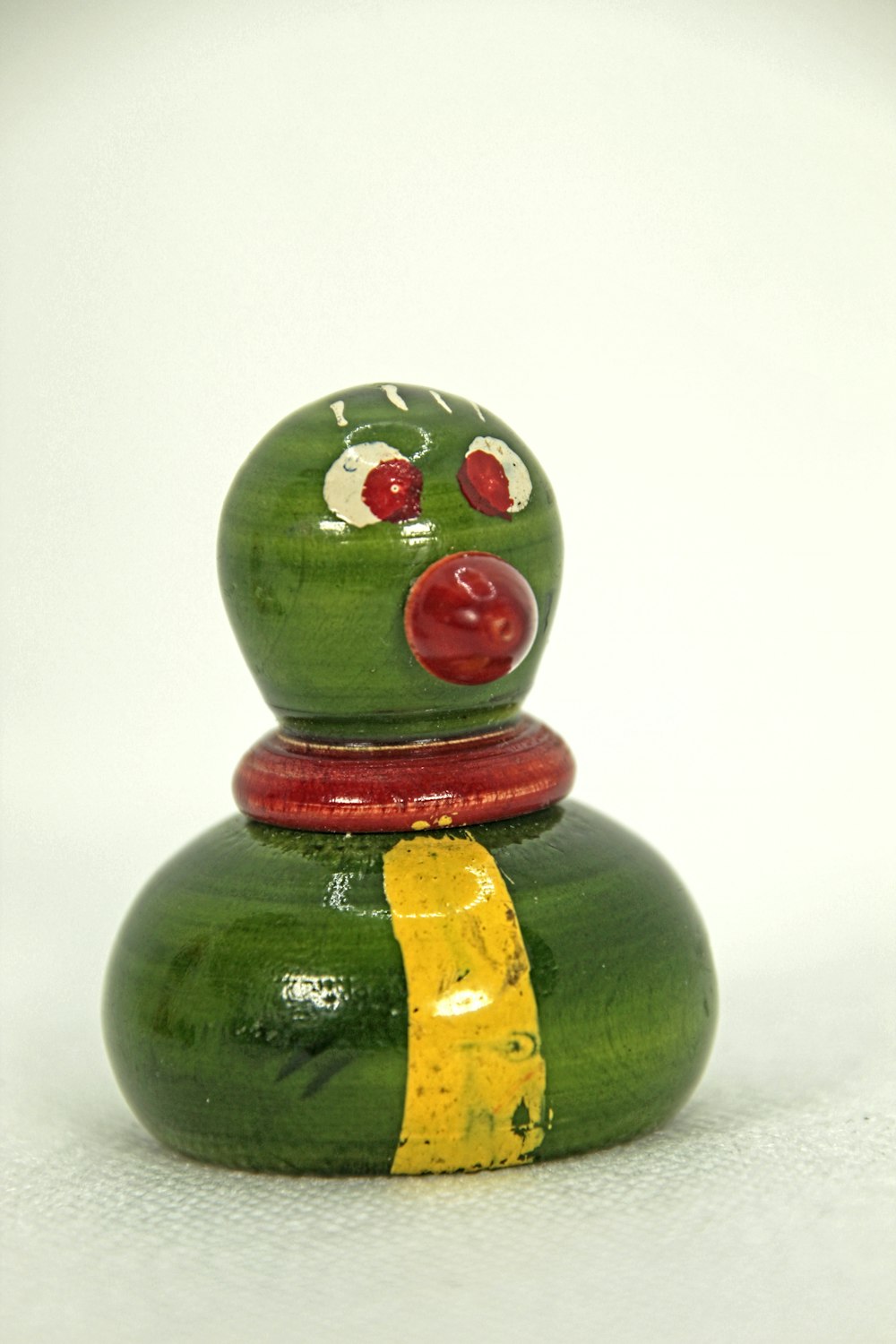 a green toy with a red nose and nose ring