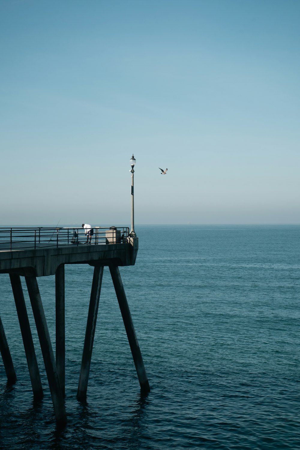 an airplane flying over a pier in the middle of the ocean