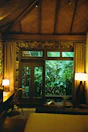 Interior of a bungalow room with natural wooden furniture and soft beige linens.