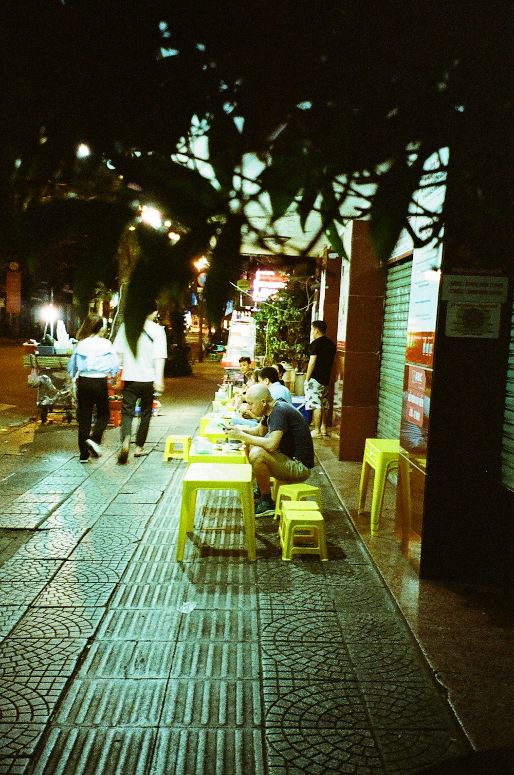 a group of people sitting at tables on a sidewalk