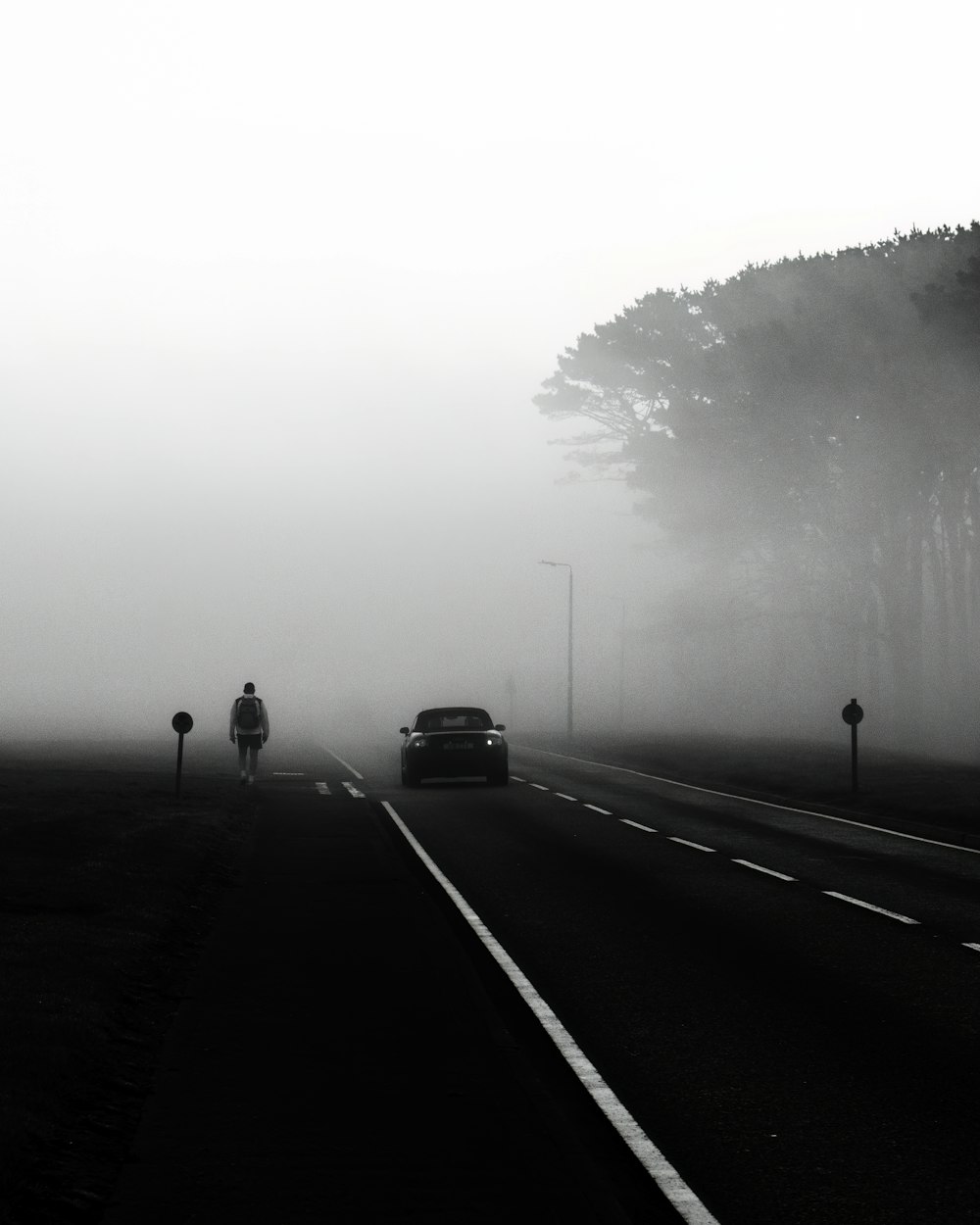 a black and white photo of a foggy road