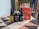 Three CBD product containers are arranged on a patterned surface. The items include two bottles with dropper tops and a pouch of gummies. The labels on the products are clearly visible, showcasing the brand 'Upstate Elevator Supply Co.'. In the background, there is a bookshelf filled with various books.