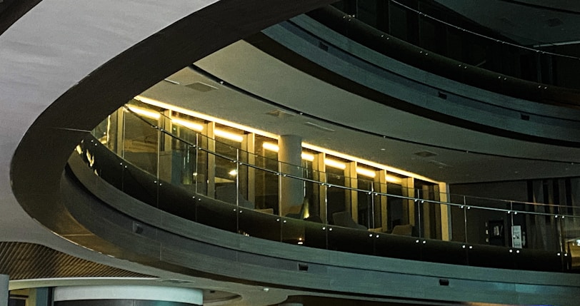 Curved interior architecture with sleek glass railings and illuminated sections, creating a modern and sophisticated atmosphere.
