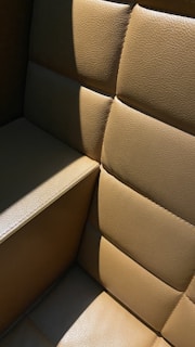 A close-up of a weathered leather jacket draped over a wooden chair outdoors, sunlight highlighting its rich texture