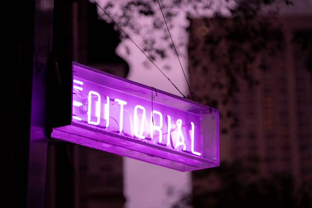 a purple neon sign hanging from the side of a building