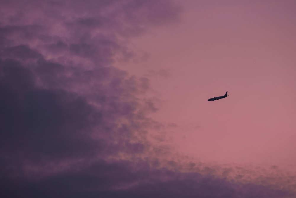 an airplane is flying in the sky at dusk