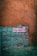 A rustic stone wall features a vibrant neon sign that reads 'Oaxaca me encantas' in bright pink and white colors. The wall, composed of earthy brown and teal stones, creates a contrast with the illuminated text. Surrounding the wall is sparse greenery, adding a natural element to the image.