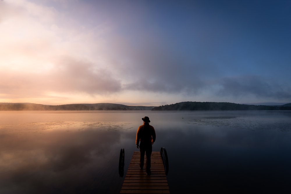 a man standing on a dock in the middle of a lake