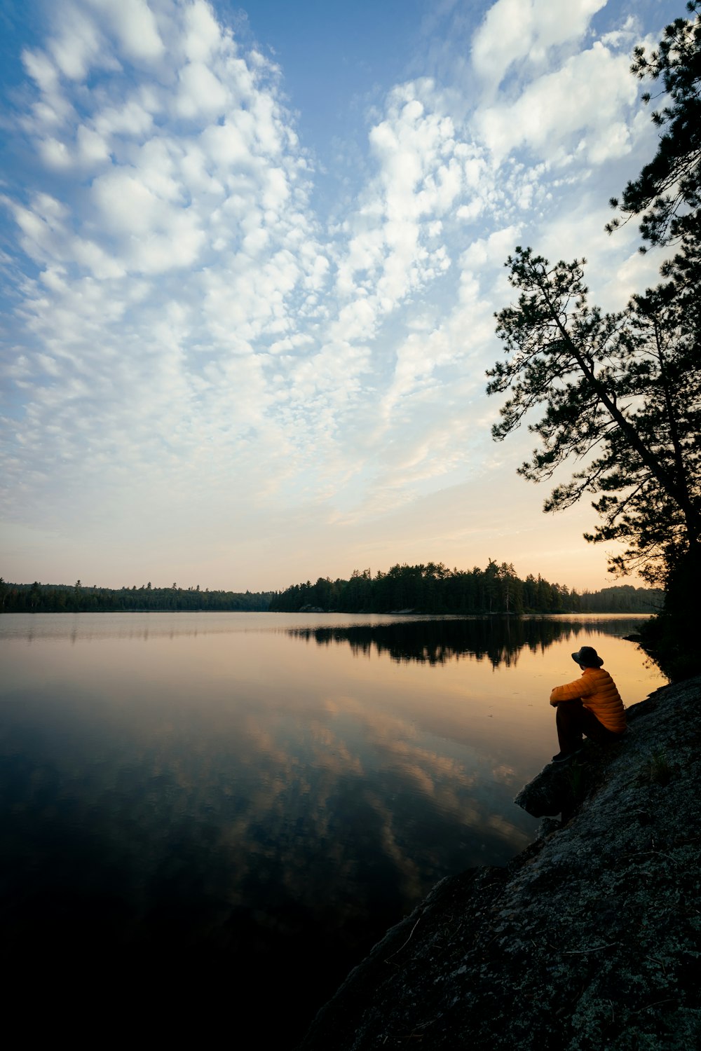 a person sitting on a rock near a body of water