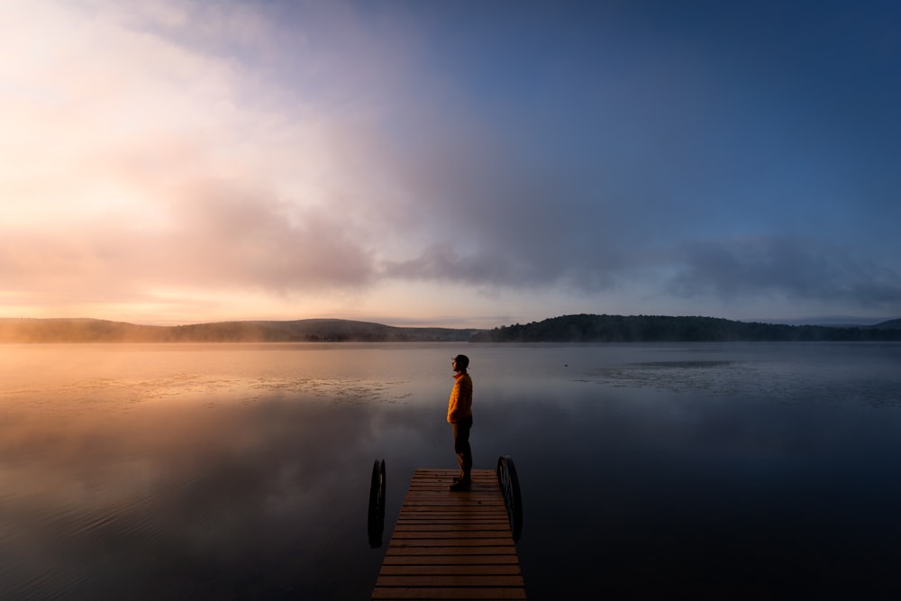 a person standing on a dock in the middle of a lake