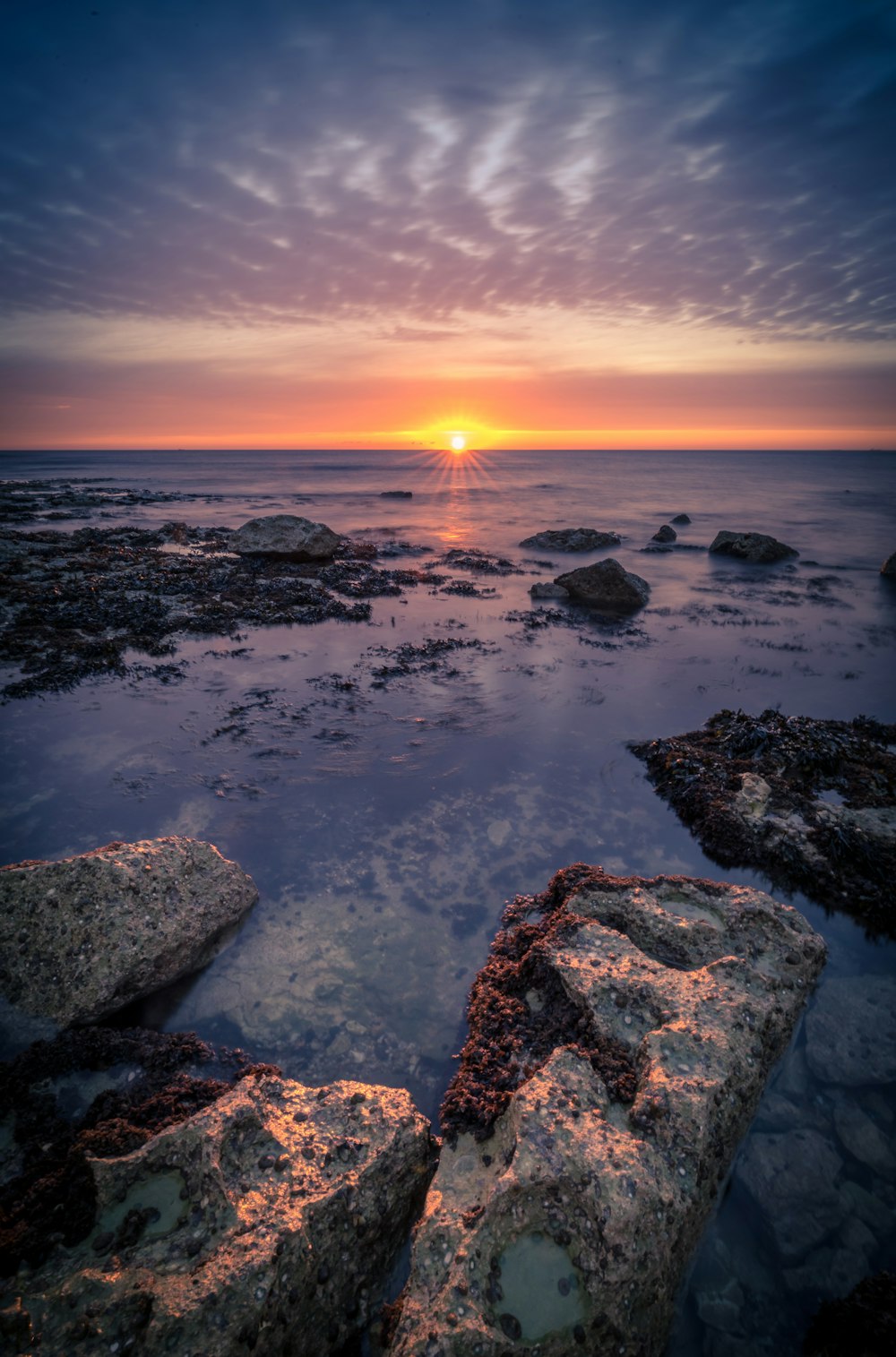 the sun is setting over the water at the beach