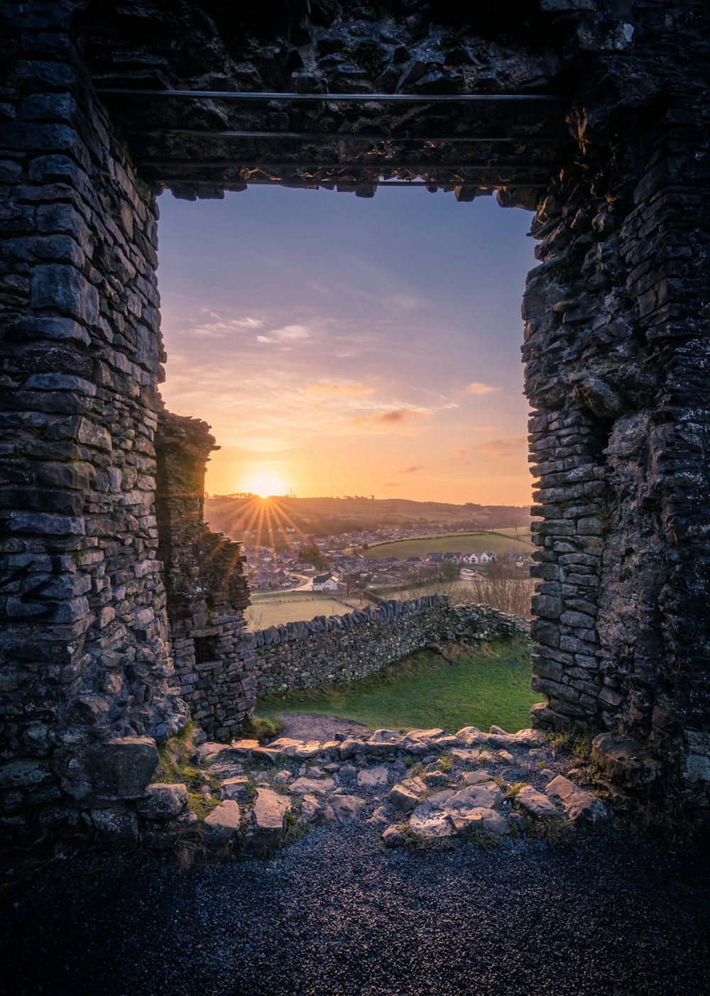the sun is setting through a window in a stone structure