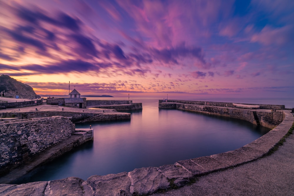 a body of water surrounded by rocks under a cloudy sky