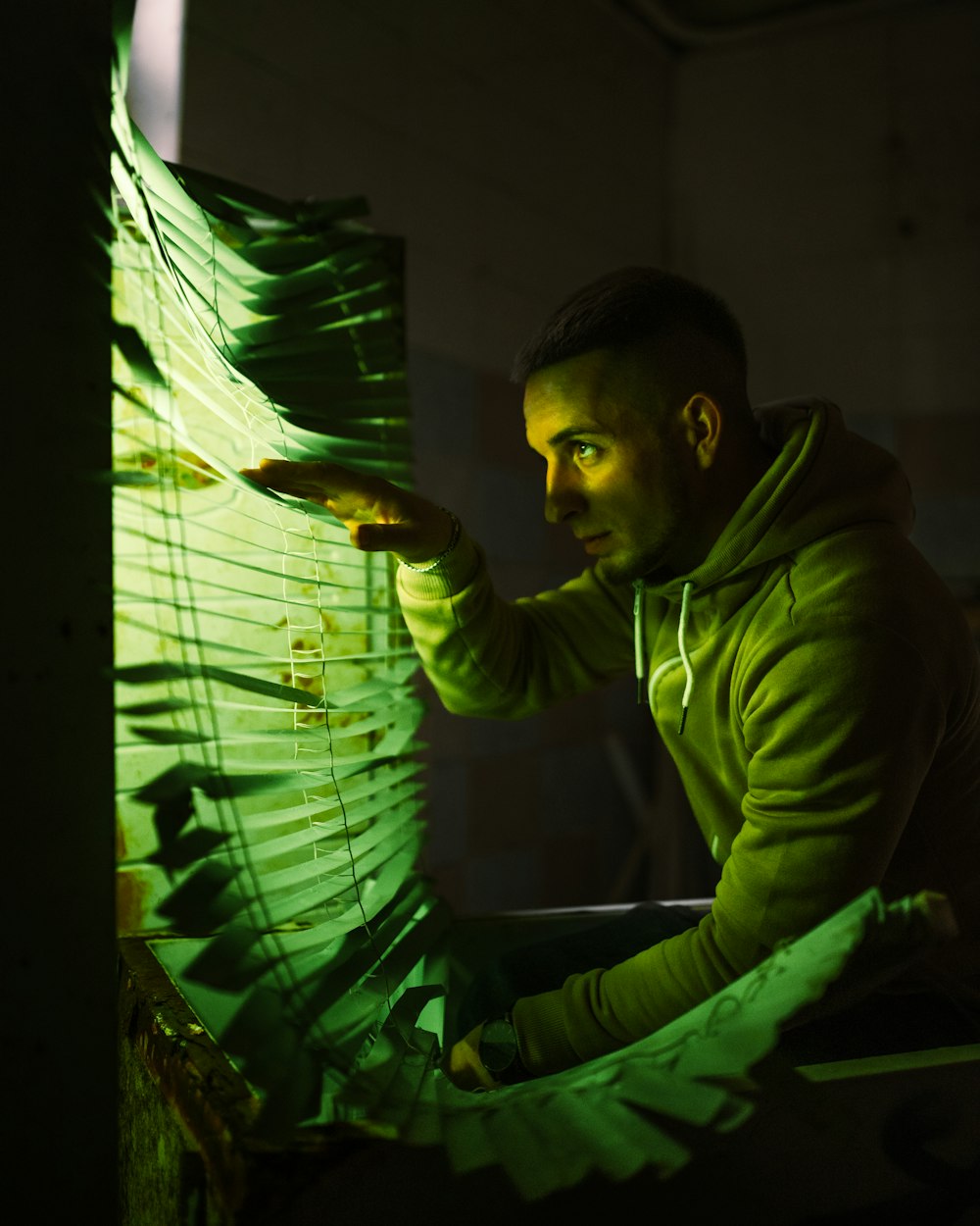 a man in a green hoodie working on a piece of art