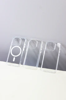 A lineup of various phone cases displayed on a minimalist white table with natural sunlight