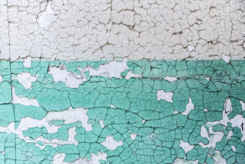 a green and white wall with peeling paint