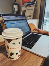 Close-up of a landlord reviewing tenant applications on a laptop with a cup of coffee nearby.