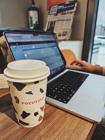 A close-up of a journalist typing rapidly on a laptop with a cup of coffee nearby.