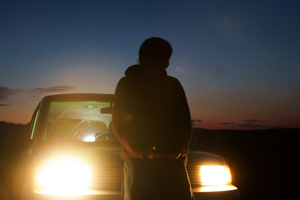 a man standing in front of a car at night